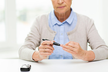 Image showing senior woman with glucometer checking blood sugar