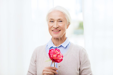 Image showing happy smiling senior woman with flower at home