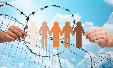 Image showing hands holding people pictogram over barb wire