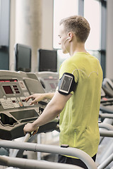 Image showing man with smartphone exercising on treadmill in gym