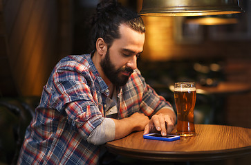 Image showing man with smartphone and beer texting at bar