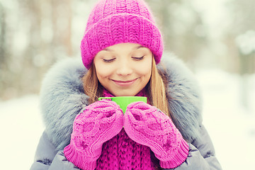 Image showing smiling young woman with cup in winter forest