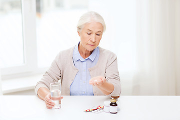 Image showing senior woman with water and medicine at home