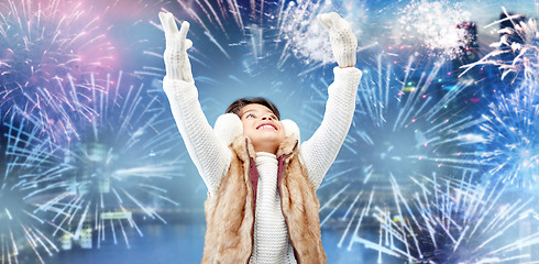 Image showing happy little girl wearing earmuffs over firework