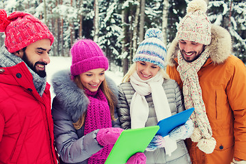 Image showing smiling friends with tablet pc in winter forest