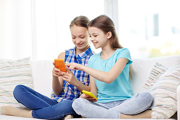 Image showing happy girls with smartphones sitting on sofa