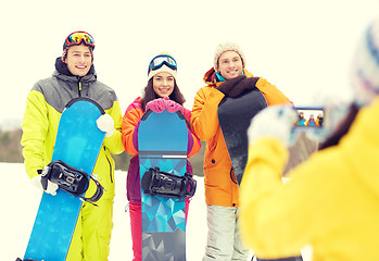 Image showing happy friends with snowboards and smartphone