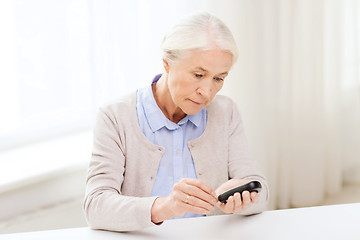 Image showing senior woman with glucometer checking blood sugar