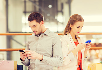 Image showing couple with smartphones and shopping bags in mall