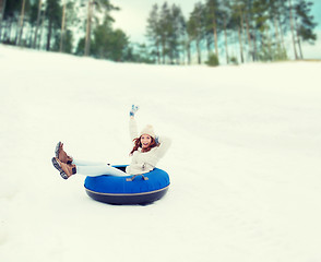 Image showing happy teenage girl sliding down on snow tube