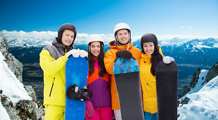 Image showing happy friends in helmets with snowboards outdoors