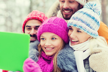 Image showing smiling friends with tablet pc in winter forest