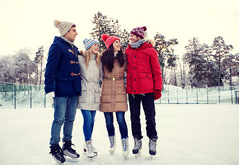 Image showing happy friends ice skating on rink outdoors