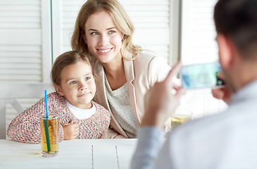 Image showing happy family picturing by smartphone at restaurant