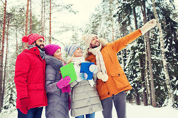 Image showing smiling friends with tablet pc in winter forest