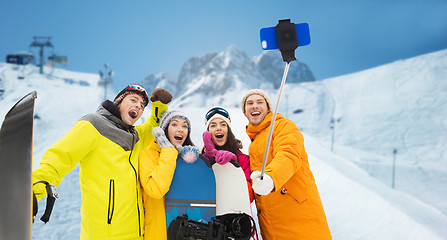 Image showing happy friends with snowboards and smartphone