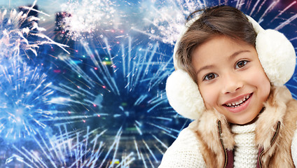 Image showing happy little girl wearing earmuffs over firework