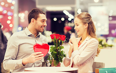 Image showing happy couple with present and flowers in mall