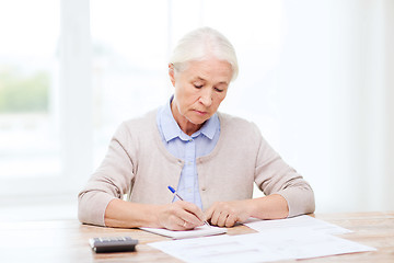 Image showing senior woman with papers and calculator at home