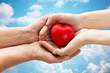 Image showing senior and young woman hands holding red heart