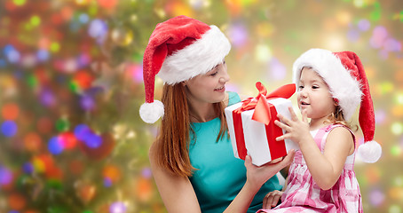 Image showing happy mother and child in santa hats with gift box