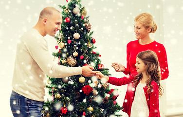 Image showing smiling family decorating christmas tree at home