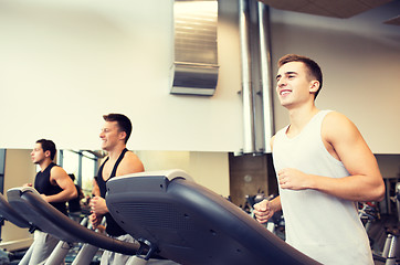 Image showing smiling men exercising on treadmill in gym