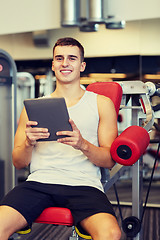 Image showing smiling young man with tablet pc computer in gym