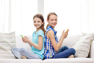 Image showing happy girls with smartphones sitting on sofa