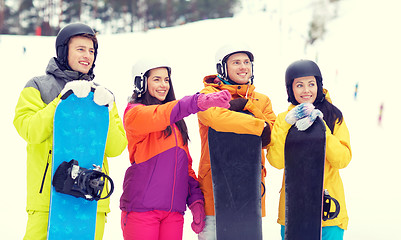 Image showing happy friends in helmets with snowboards