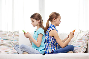 Image showing girls with smartphones sitting on sofa at home