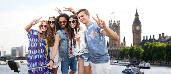 Image showing smiling hippie friends with selfie stick in london