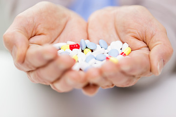 Image showing close up of senior woman hands with pills