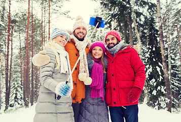 Image showing smiling friends with smartphone in winter forest