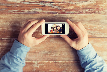 Image showing close up of male hands with photo on smartphone