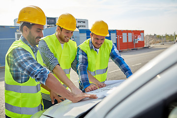 Image showing close up of builders with blueprint on car hood