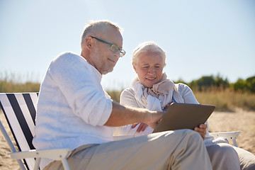 Image showing happy senior couple with tablet pc on summer beach