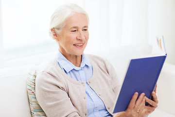 Image showing happy smiling senior woman reading book at home