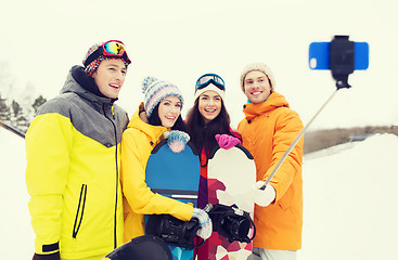 Image showing happy friends with snowboards and smartphone