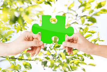 Image showing hands with green puzzle over natural background