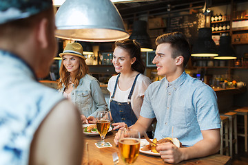 Image showing happy friends eating and drinking at bar or pub