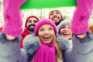 Image showing smiling friends with tablet pc in winter forest