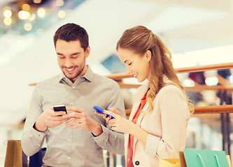 Image showing couple with smartphones and shopping bags in mall