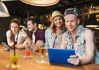 Image showing happy friends with tablet pc and drinks at bar