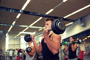 Image showing young men flexing muscles with barbells in gym