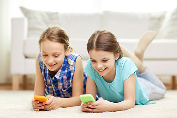 Image showing happy girls with smartphones lying on floor