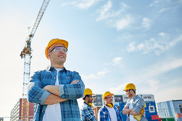 Image showing group of smiling builders in hardhats outdoors