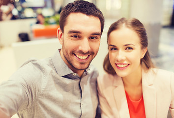 Image showing happy couple taking selfie in mall or office