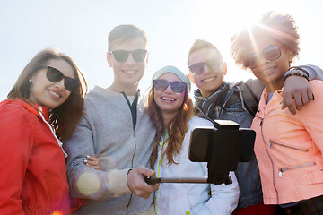 Image showing friends taking selfie with smartphone on stick