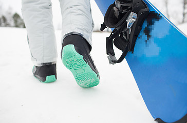 Image showing close up of snowboarder walking with snowboard